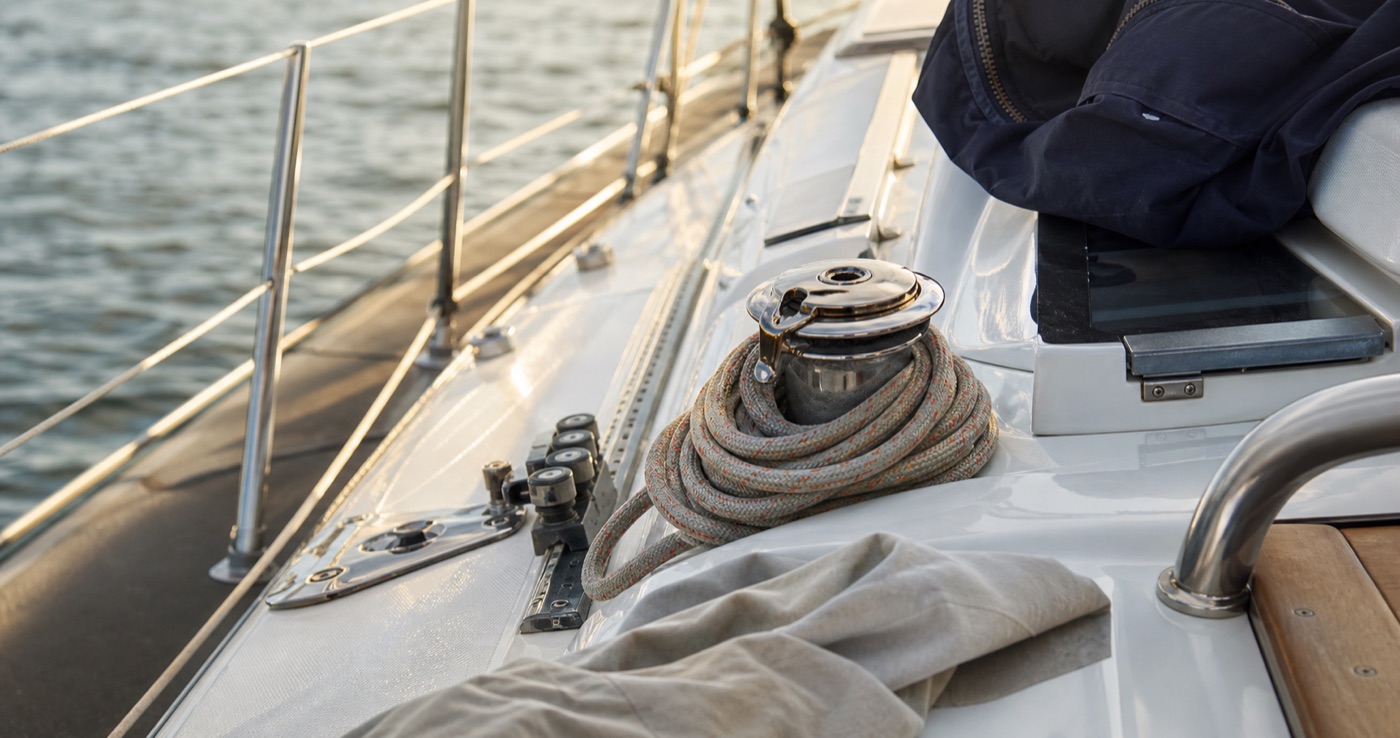 Clean yacht deck detail with coiled line and stainless fittings in harbour light
